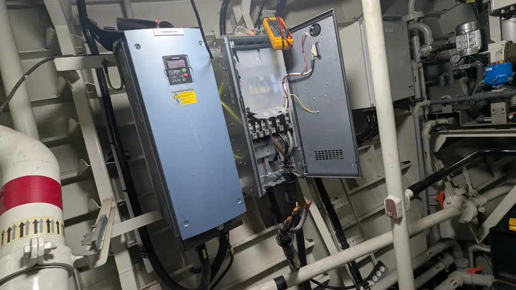 Frequency drive with the cover off and a multimeter clamped to the terminals