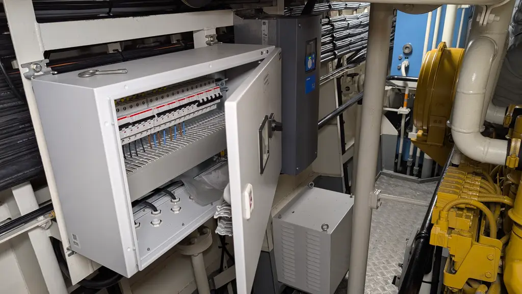 Grey wall cabinet with the door open, showing terminals and breakers
