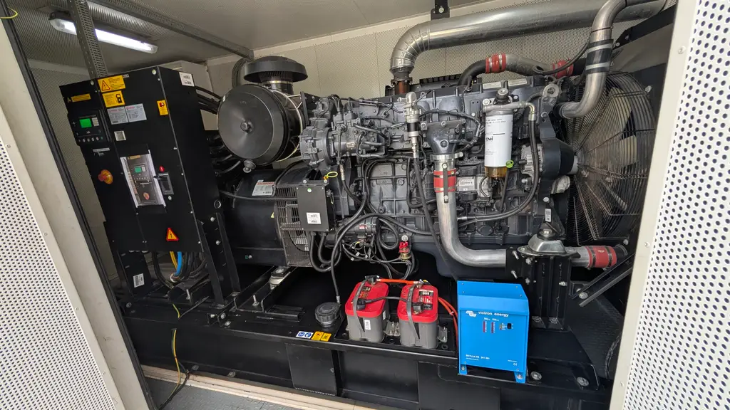Diesel generator set in its enclosure, with starter batteries and a charger