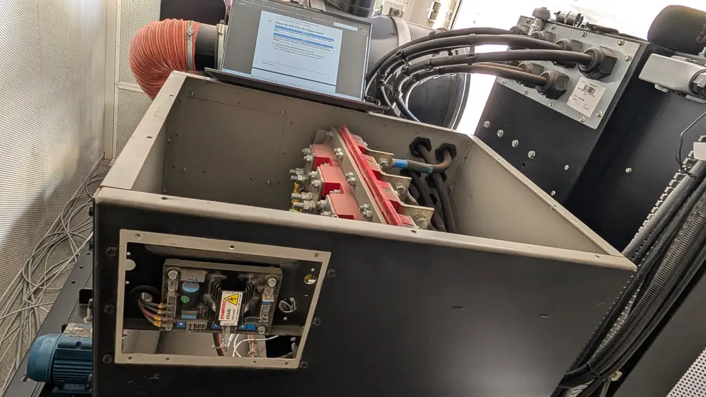 Inside a switchboard cabinet: copper busbars, cabling and a laptop on top